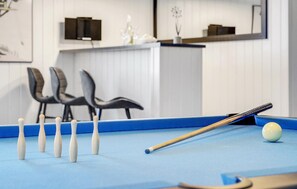 A pool table with a cue stick and billiard balls, a blue felt surface, and a white wall with a decorative item. - Cozy home in Stege with sauna (Stege)
