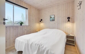 A bedroom with a bed, a window, a wall-mounted lamp, and a small shelf. - Cozy home in Stege with sauna (Stege)
