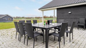 An outdoor patio with a table and chairs, a beverage setup, and a view of the surrounding landscape. - Cozy home in Stege with sauna (Stege)