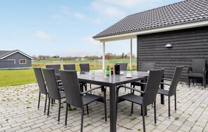 An outdoor patio with a table and chairs, a beverage setup, and a view of the surrounding landscape. - Cozy home in Stege with sauna (Stege)