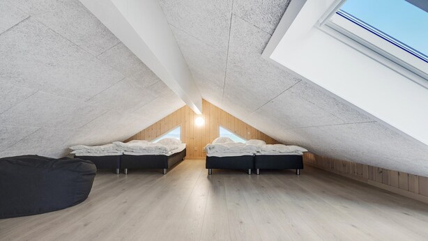A small attic bedroom with two beds, wooden flooring, and a skylight. - Cozy home in Stege with sauna (Stege)