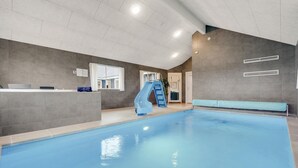 An indoor swimming pool with a slide, a reception desk, and a window. - Cozy home in Stege with sauna (Stege)
