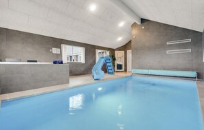 An indoor swimming pool with a slide, a reception desk, and a window. - Cozy home in Stege with sauna (Stege)