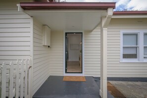 A house entrance with a covered porch, a door leading inside, and a small window on the right. - Comfortable Family Home in Newstead (Newstead)