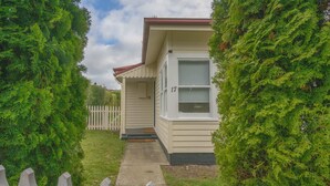 A single-story house with a front porch, a picket fence, and a number 17 on the door. - Comfortable Family Home in Newstead (Newstead)