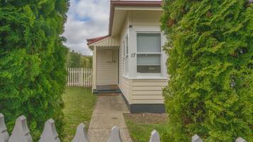 A single-story house with a front porch, a picket fence, and a number 17 on the door.
