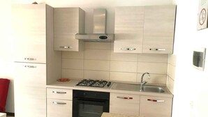 A compact kitchen with a gas stove, oven, and a stainless steel sink. - Holiday apartment mit Klimaanlage und Balkon (Jesolo)