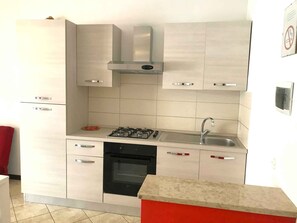 A compact kitchen with a gas stove, oven, and a stainless steel sink. - Holiday apartment mit Klimaanlage und Balkon (Jesolo)