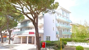A multi-story hotel with balconies, a red mailbox, and a tree in the foreground. - Holiday apartment mit Klimaanlage und Balkon (Jesolo)