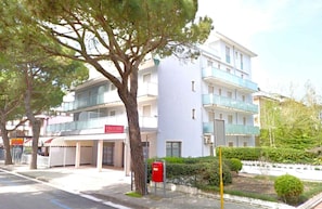 A multi-story hotel with balconies, a red mailbox, and a tree in the foreground. - Holiday apartment mit Klimaanlage und Balkon (Jesolo)