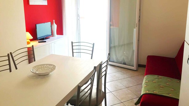 A dining area with a table, chairs, a laptop, and a vase. - Holiday apartment mit Klimaanlage und Balkon (Jesolo)