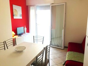 A dining area with a table, chairs, a laptop, and a vase. - Holiday apartment mit Klimaanlage und Balkon (Jesolo)
