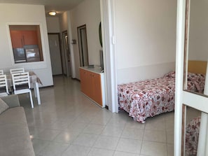 A compact living space with a kitchenette, a dining area, and a bed. - Holiday apartment with air conditioning and balcony with sea view (Lido di Jesolo)