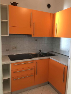 Eine Küche mit orangefarbenen Schränken, einem schwarzen Herd und einer Spüle.