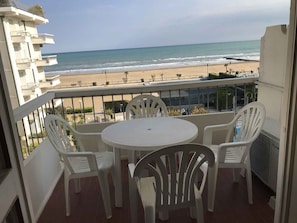 Ein Balkon mit Tisch und Stühlen mit Blick auf einen Strand.