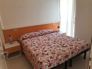 Ein Schlafzimmer mit einem Bett, Nachttischen, einem Schreibtisch und einem Fenster mit Vorhängen.