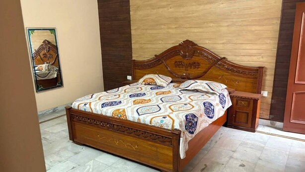 Een slaapkamer met een houten bed, een nachtkastje en een wandplank.