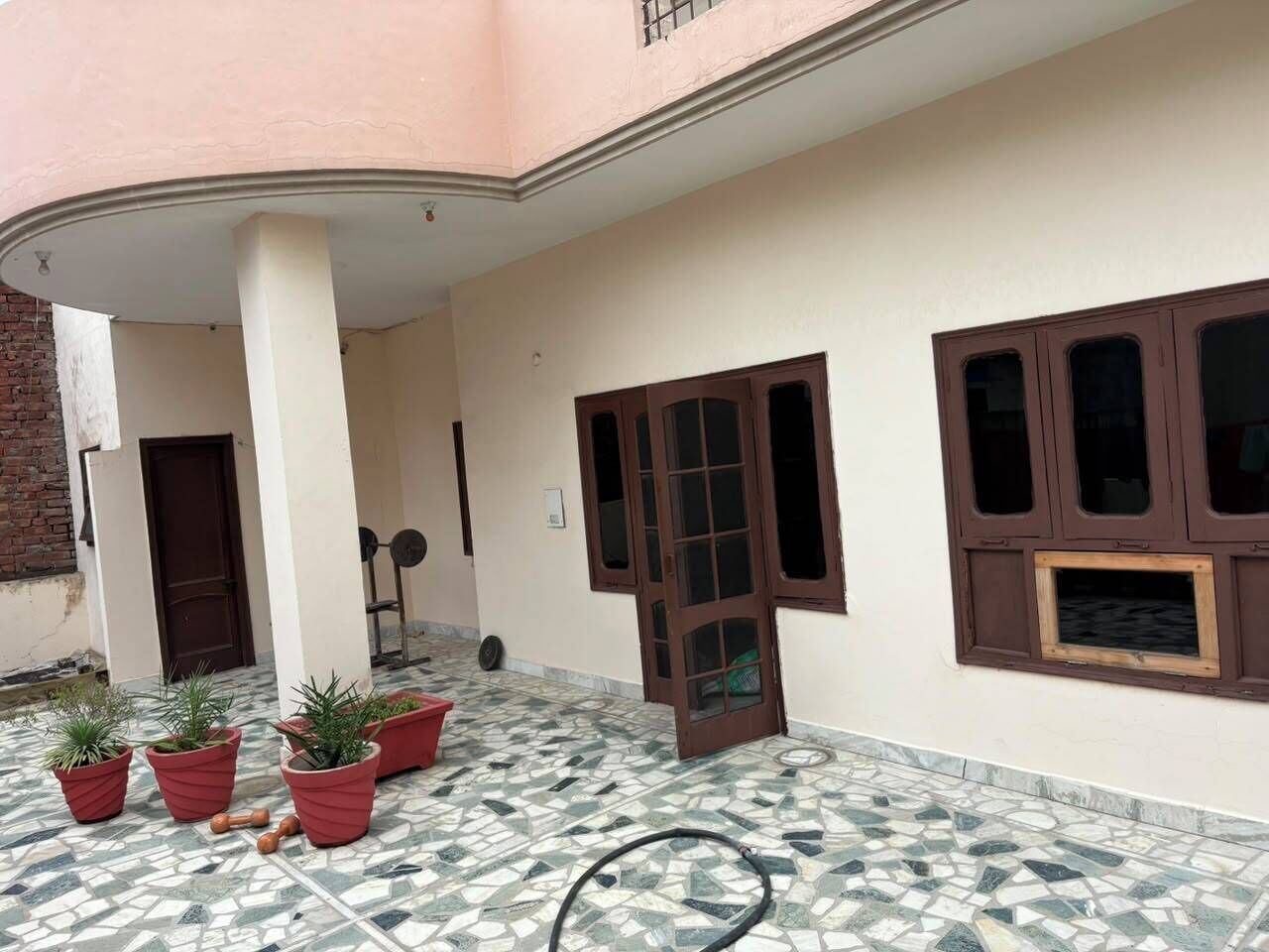 A building with a tiled floor, a door, and potted plants.