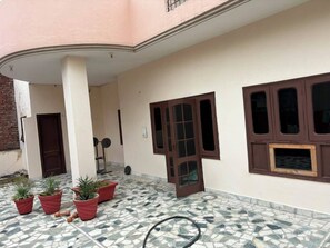 A building with a tiled floor, a door, and potted plants.