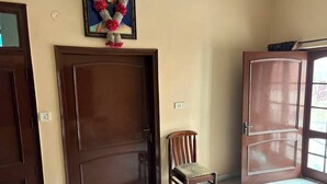 Een kamer met een grote houten deur, een kleine houten stoel en een lijst met een afbeelding aan de muur.