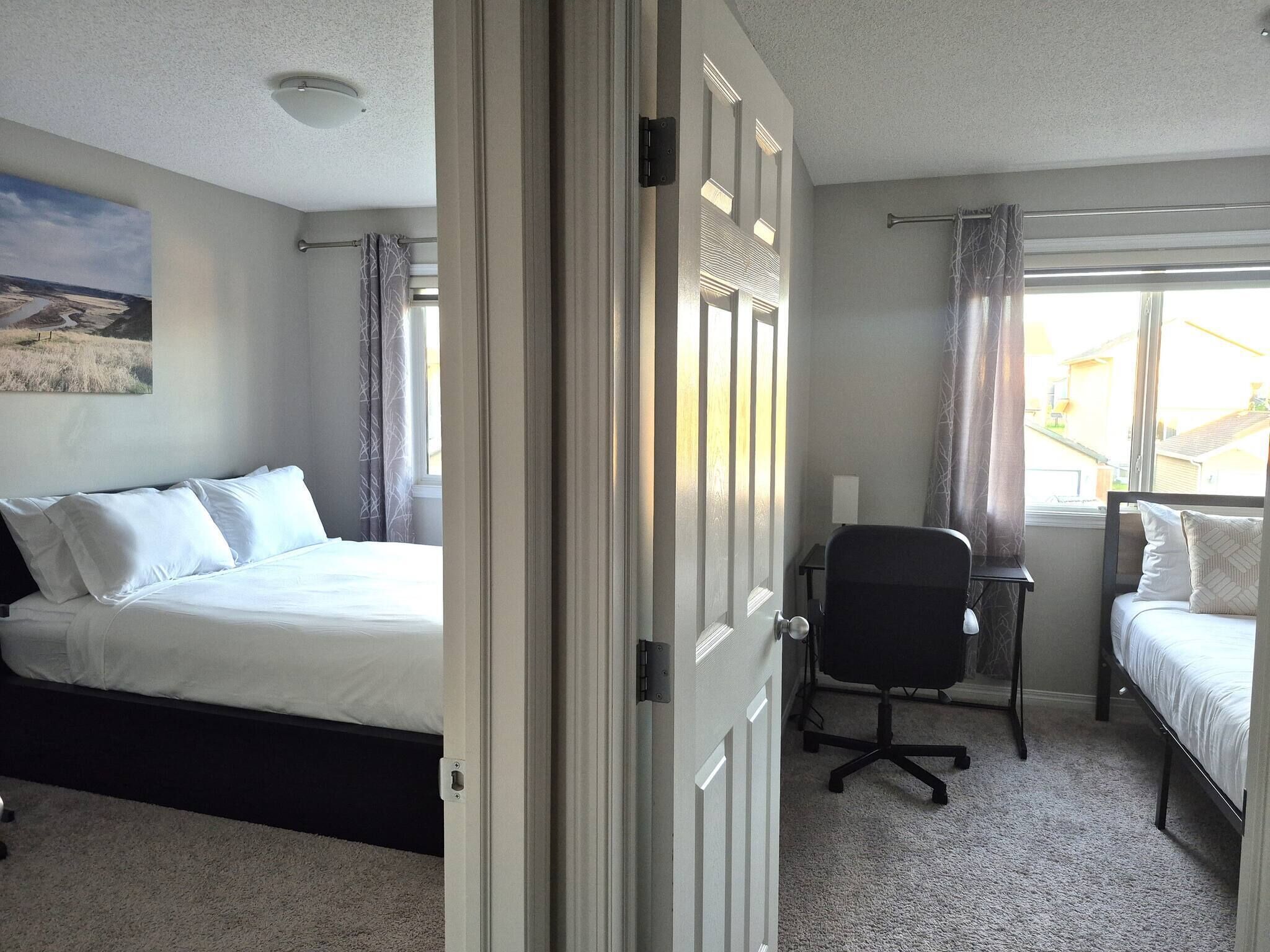 A hotel room with a bed, a desk, a chair, and a window with curtains.