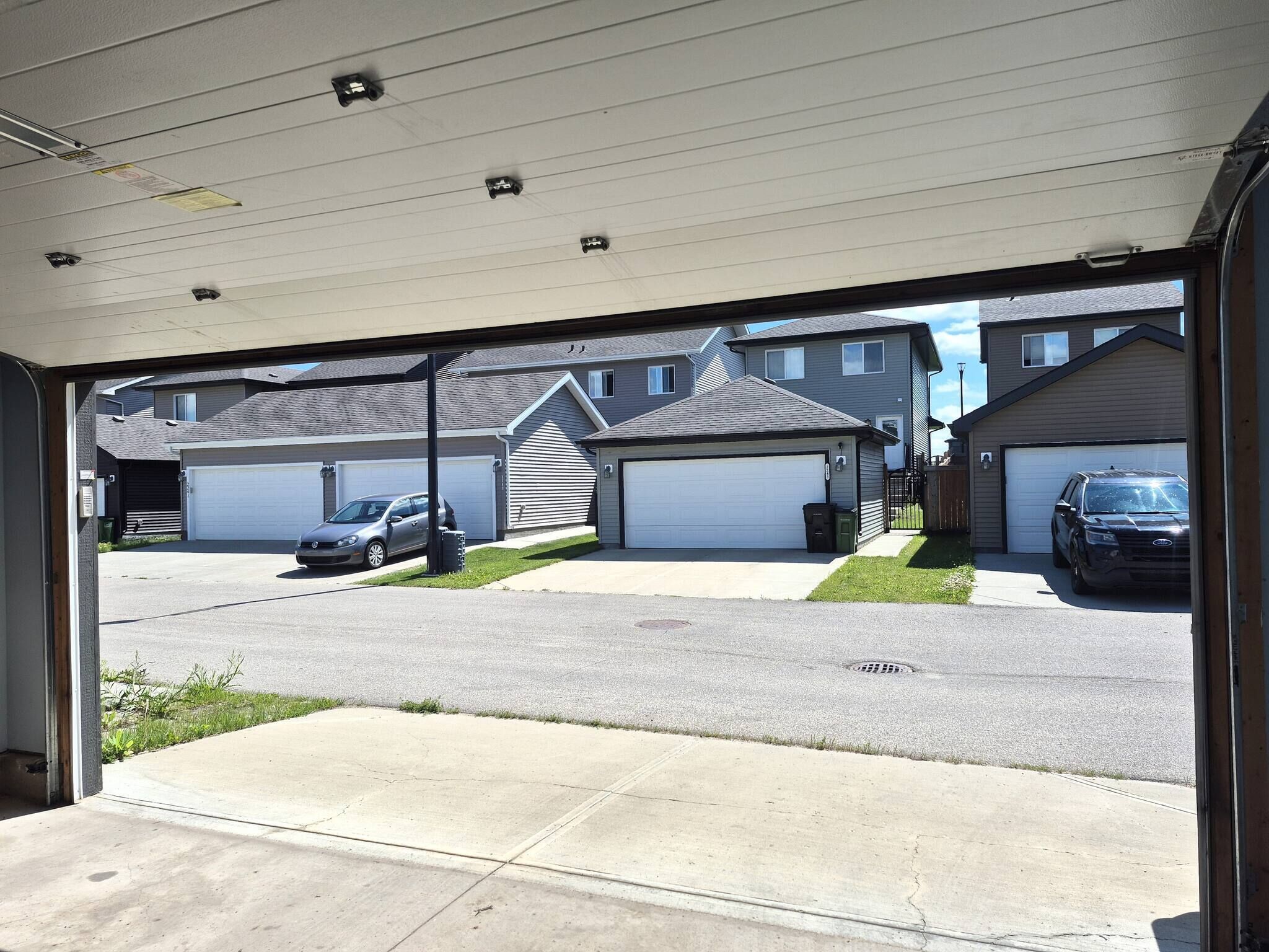 A residential street with houses, garages, and parked cars.