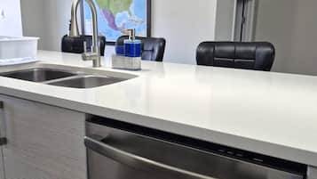 A modern kitchen with stainless steel appliances, a white countertop, and a map on the wall.