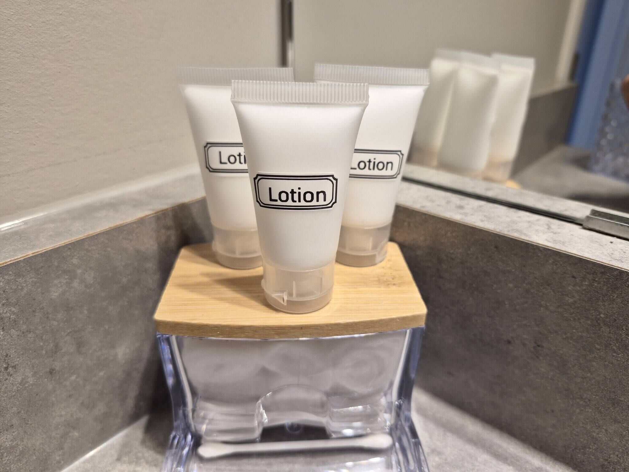 Mehrere Lotiontuben auf einem Holztablett in einem Badezimmer.