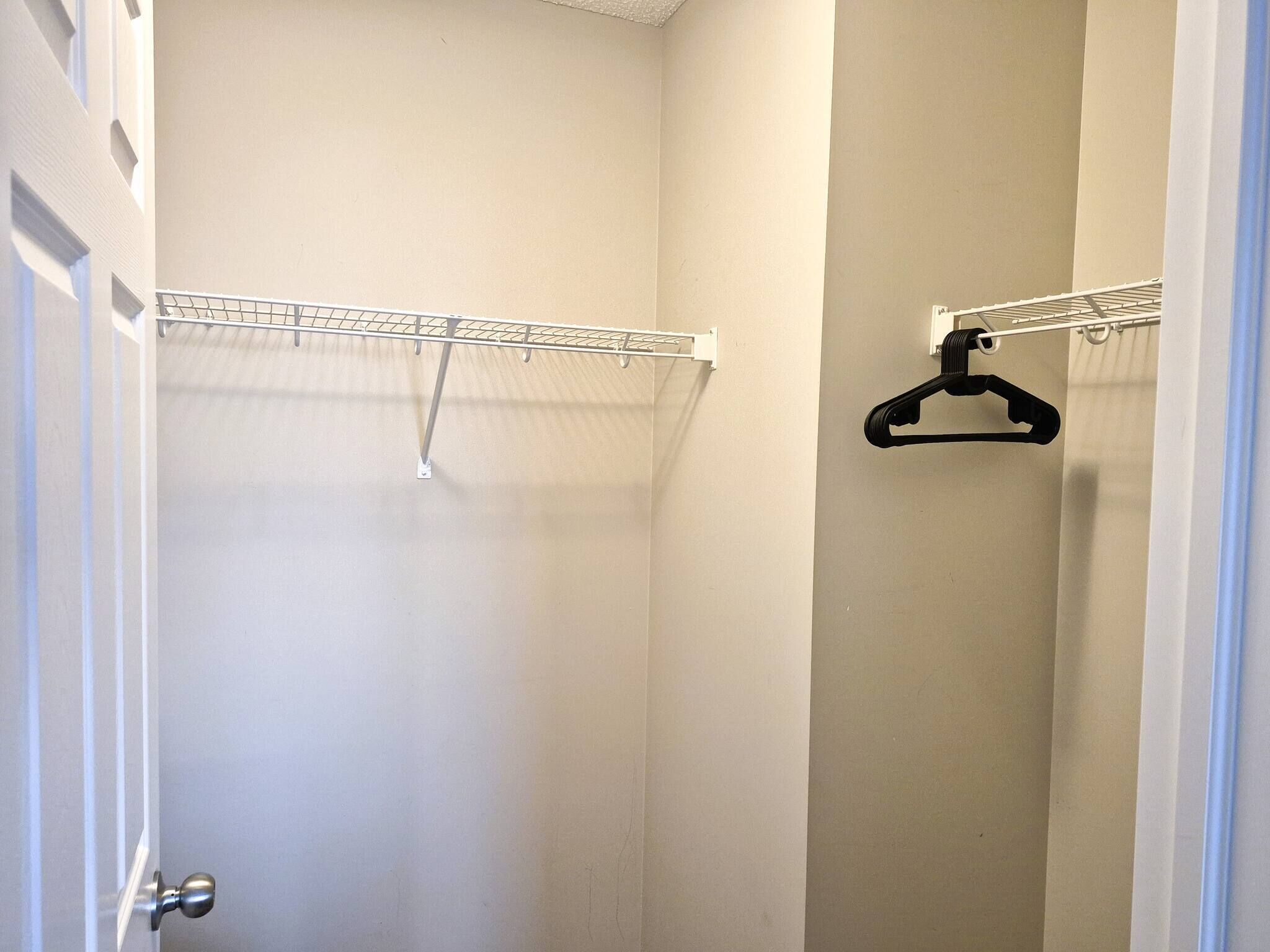 Ein Schrank mit einer Kleiderstange und einem schwarzen Kleiderbügel.