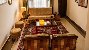 Una sala de estar con sofá, sillones, una mesa de centro y un tapete estampado.