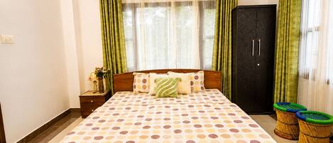A bedroom with a bed, a nightstand, a wardrobe, and a window with curtains.