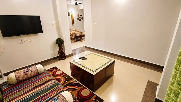 Una sala de estar con un sofá, una mesa de centro, un televisor de pantalla plana y un ventilador de techo.