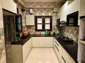 A compact kitchen with a central island, a window with frosted glass, and a tiled backsplash.