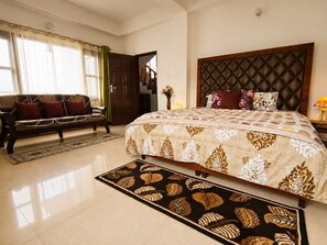 A hotel room with a large bed, a sofa, a rug, and a door leading to another room. - Adorable 3-bedroom luxury house with modular kitchen in peaceful Jutogh (Jutogh)