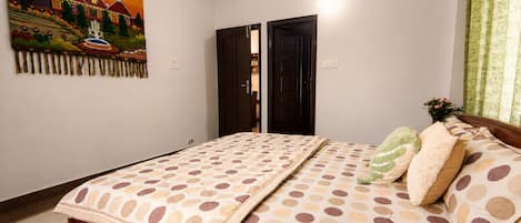 A bedroom with a bed, a painting, and a door.