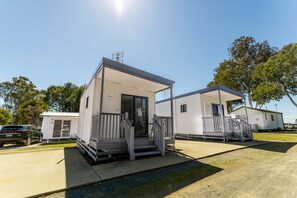 A row of mobile homes with a covered porch and a small staircase leading to the entrance.