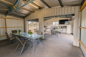 Amplio espacio interior con una gran mesa y sillas, una cocina equipada y vistas a través de una puerta.