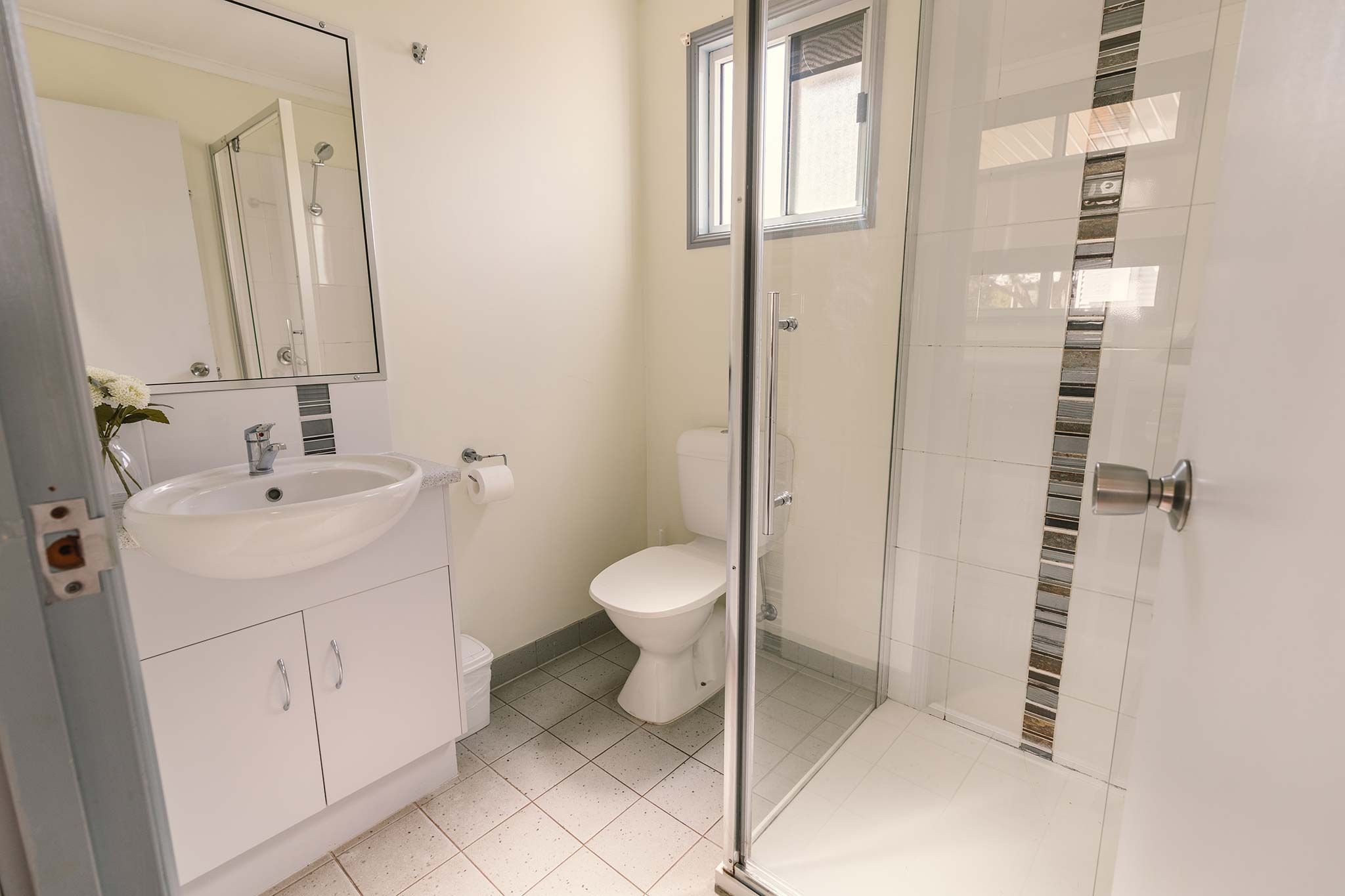 A bathroom with a white sink, toilet, and glass shower enclosure.