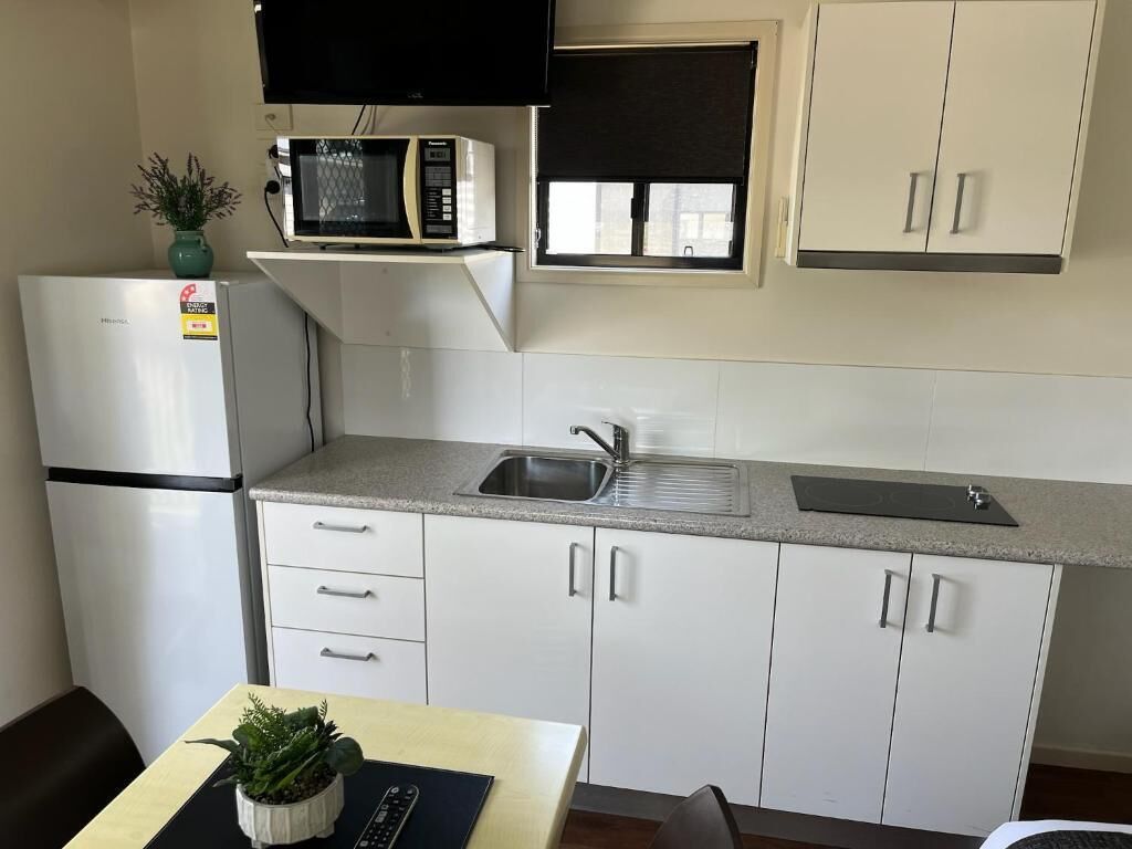 A compact kitchen with a microwave, refrigerator, and a window above the sink.