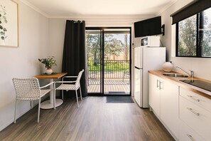 A compact kitchen with a dining area, a refrigerator, a sink, and a large window.