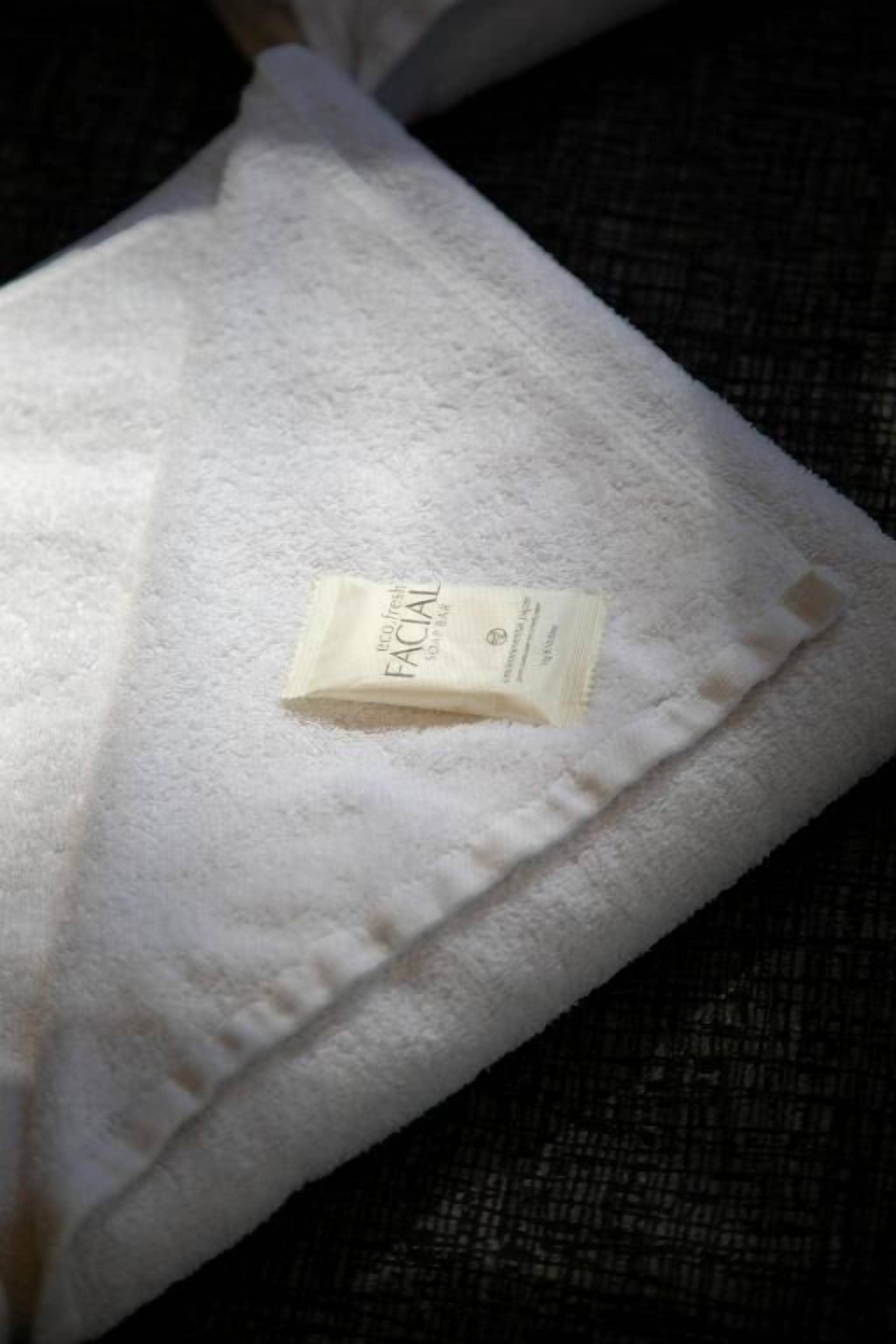 A white towel with a label on a textured surface.