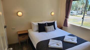 A hotel room with a bed, bedside tables, and a window with curtains.