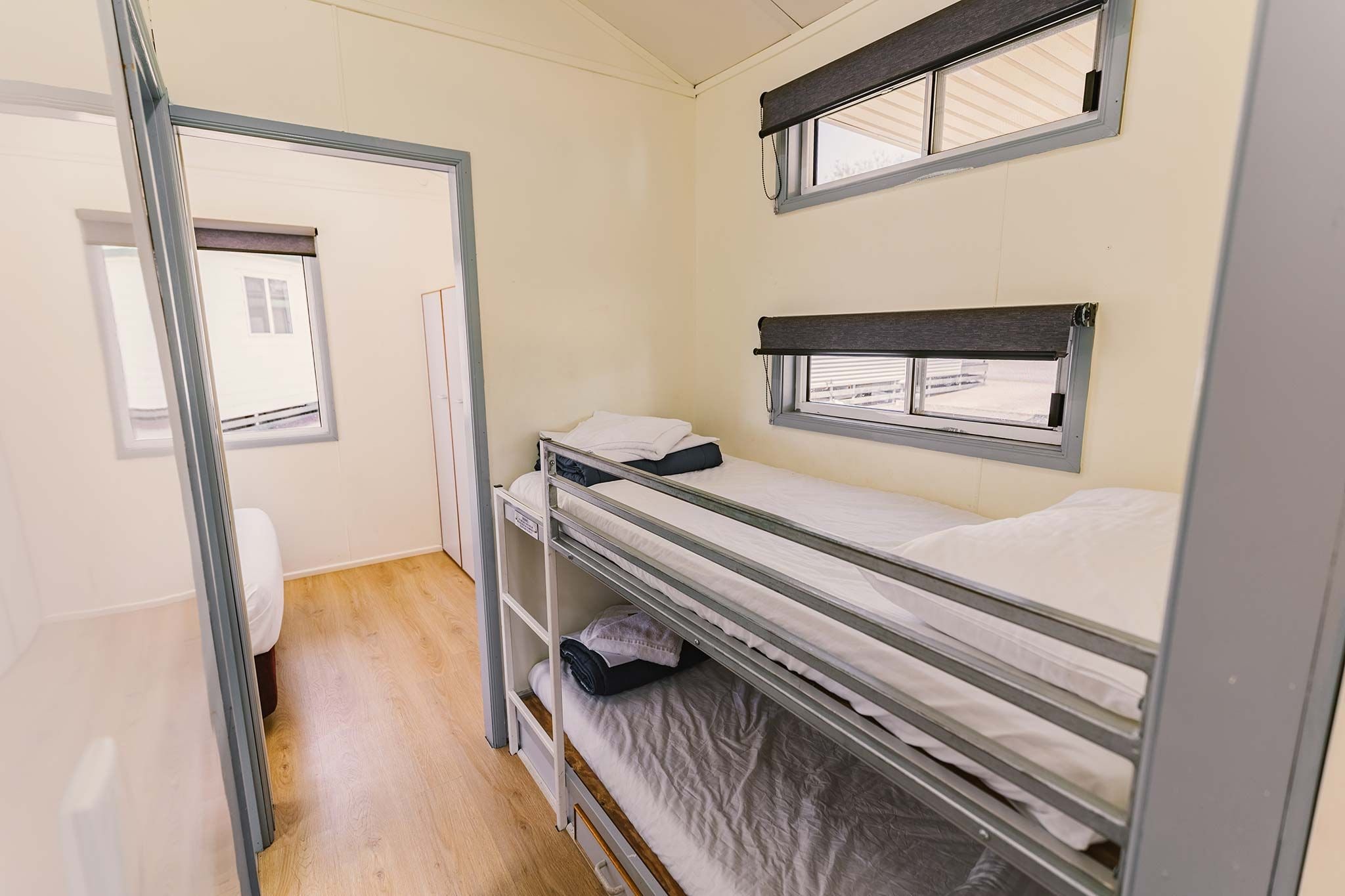 A bunk bed room with a window, a door, and a toilet.