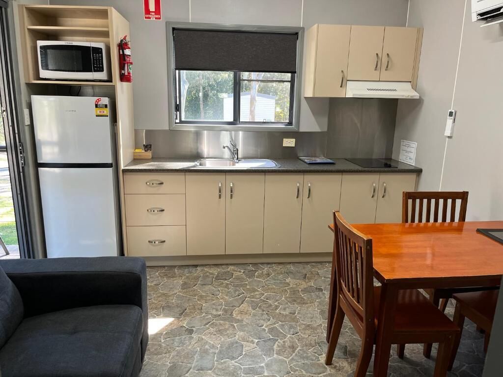 Cozinha compacta com micro-ondas, geladeira, pia e armários de madeira.