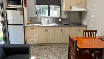 Cozinha compacta com micro-ondas, geladeira, pia e armários de madeira.