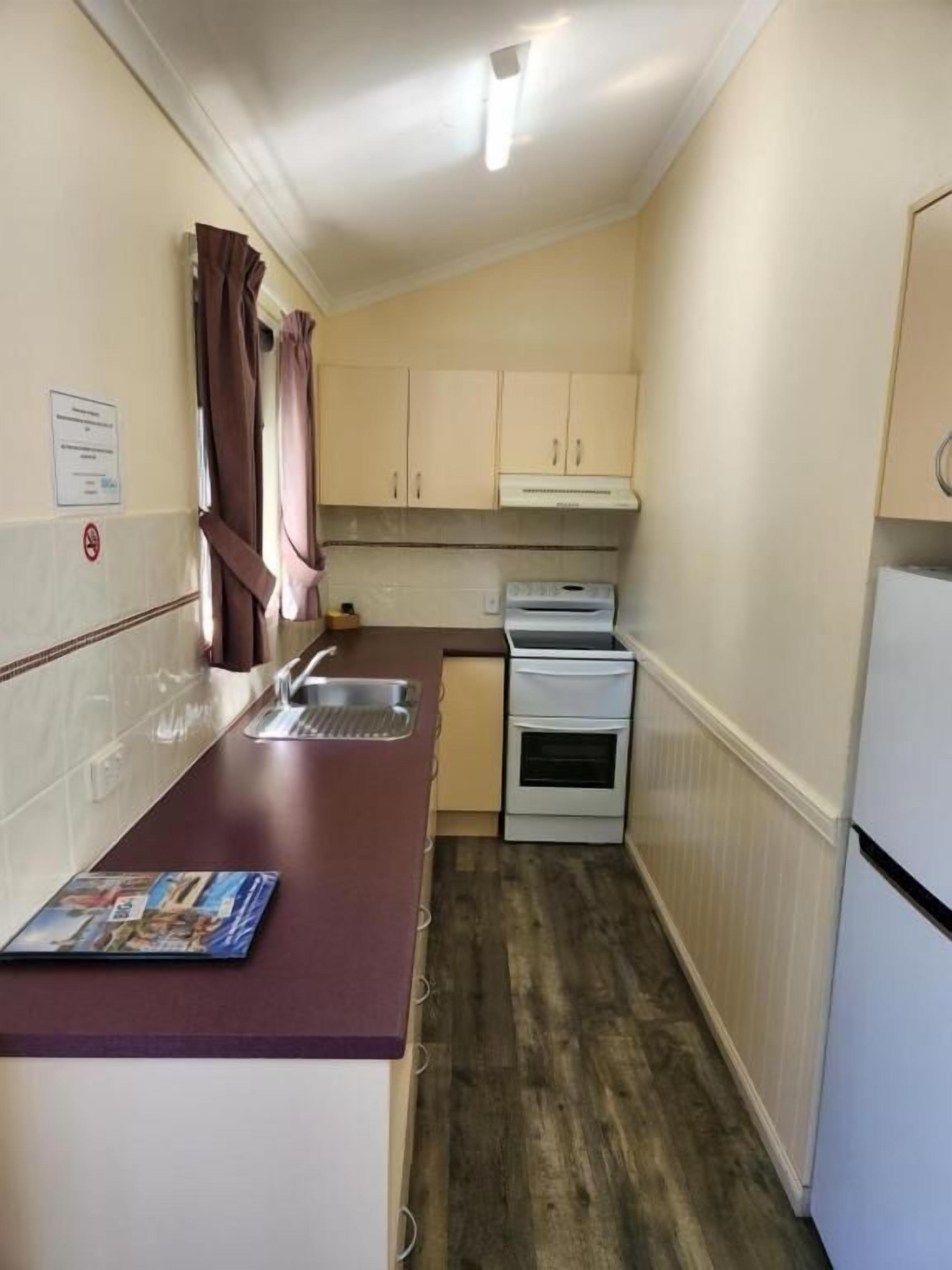 A compact kitchen with a single sink, a stove, and a refrigerator.