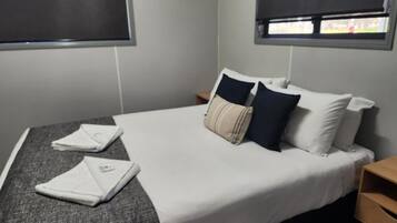Une chambre d’hôtel avec un lit, des oreillers, une table de chevet et une fenêtre.