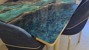 Et konferencemødebord med glasplade og marmorlignende design, omgivet af fire stole med gyldne ben.