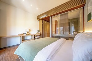 Habitación de hotel con cama, escritorio, silla y ventana con persianas.