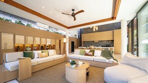 A modern living room with a sofa set, a coffee table, and a kitchen area in the background. - Villa Anaka Pererenan (Pererenan)